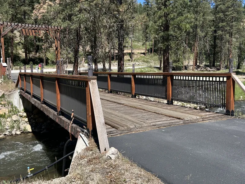 The wooden deck and timber gateway of the private bridge over Mores Creek at the property entrance.